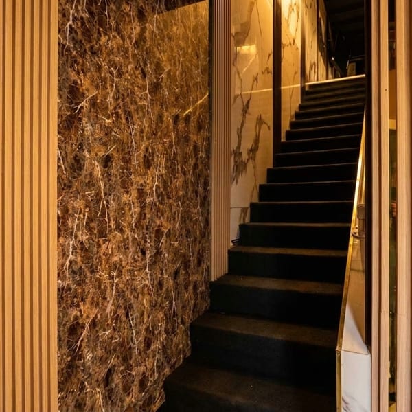 Elegant staircase with dark steps, gold railings, and marble walls with wood paneling.