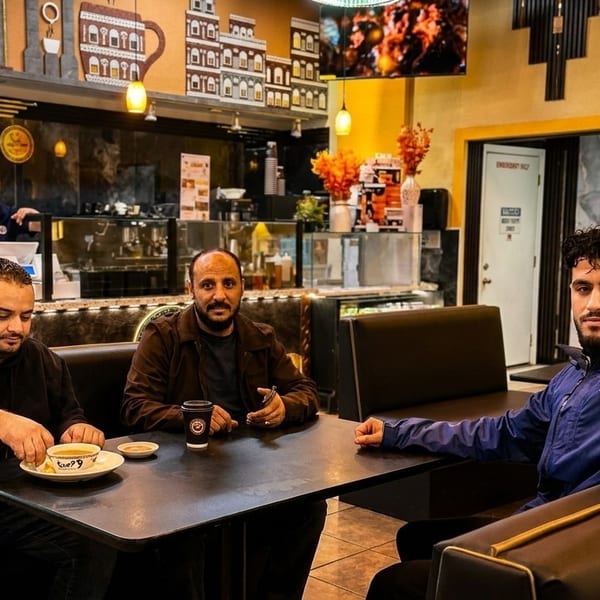 Three men seated at a table in a restaurant, with a server in the background.