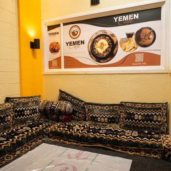 Cozy corner seating with patterned cushions and a Yemen Cafe menu display on the wall.