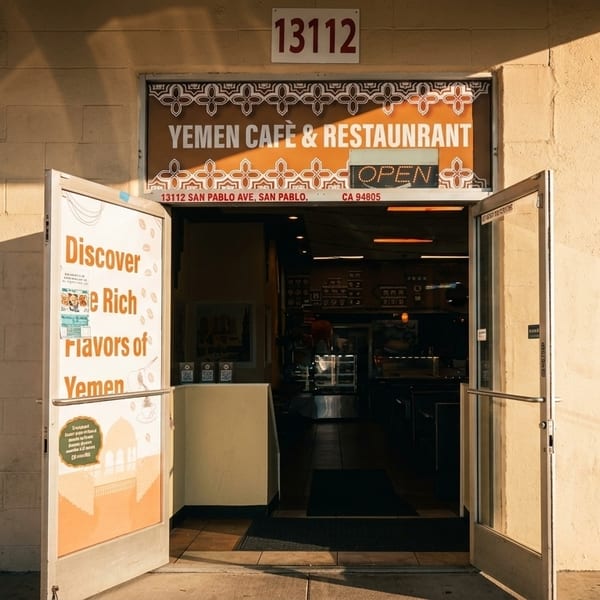 Exterior view of Yemen Cafe & Restaurant entrance with open doors and a sign advertising rich flavors.