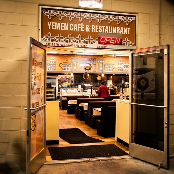 The open entrance of Yemen Cafe & Restaurant, revealing the dining area with booths and staff.