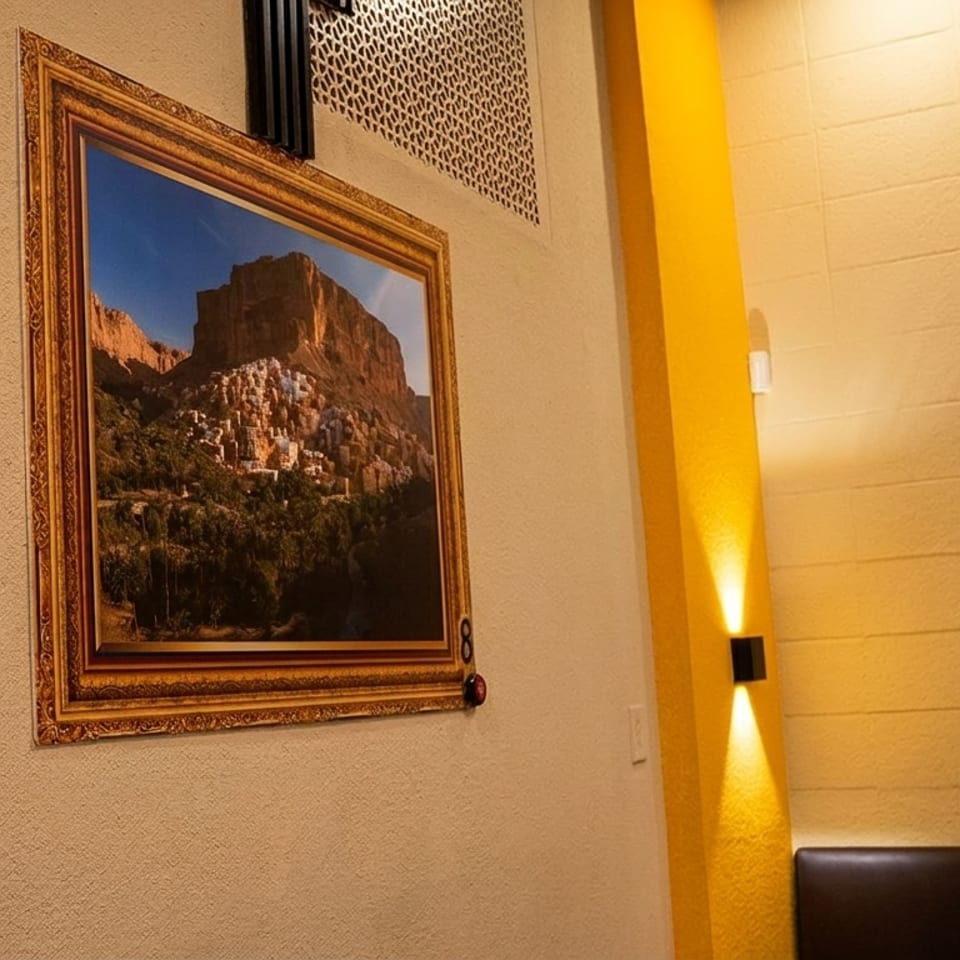 Two framed landscape paintings on textured walls, with yellow accents and modern lighting fixtures.