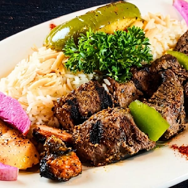 Grilled beef skewers with rice, green peppers, and pickled vegetables on a white plate.