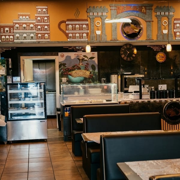 Interior of a restaurant with black booths, tables, a service counter, and decorative wall art.